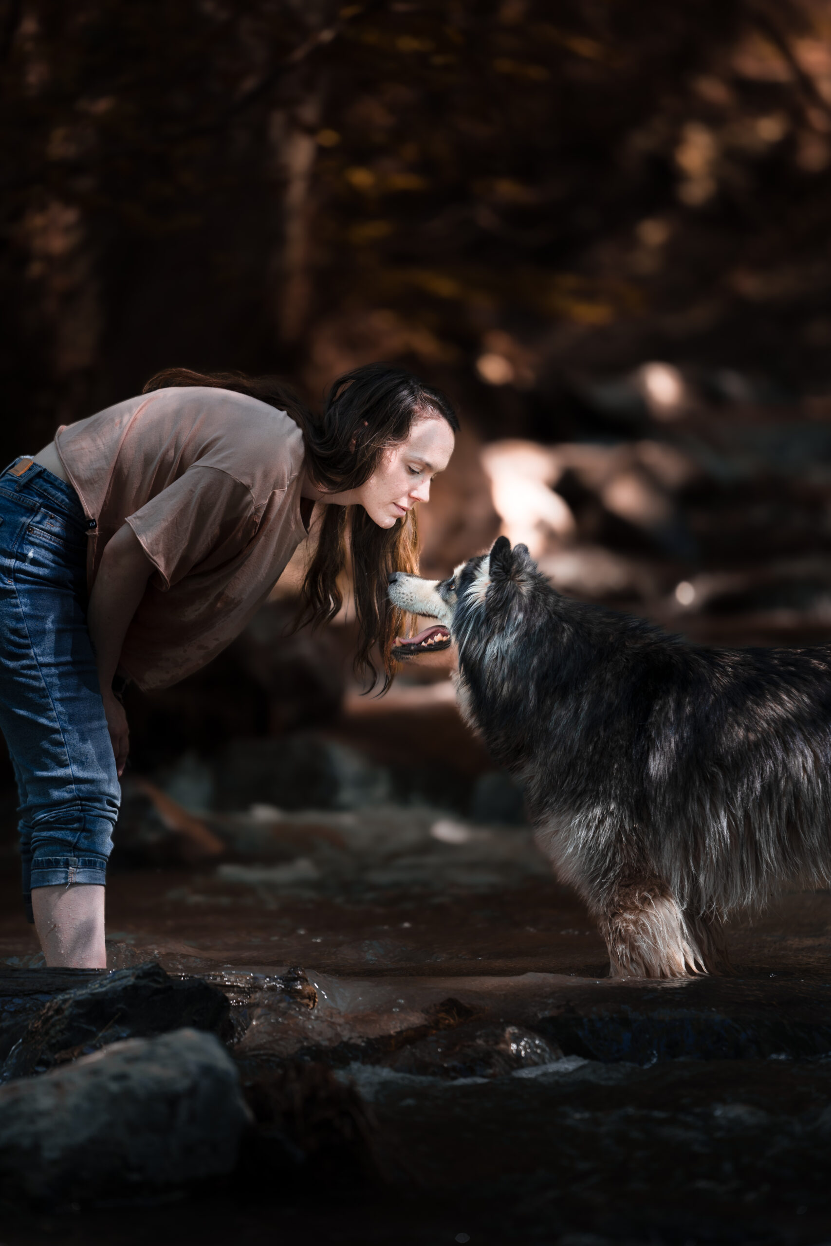 Margaux et sa malamute se regardant dans les yeux, les pieds dans l'eau de la cascade de l'Arpenaz en Savoie. Photographie prise par Coppin Studio, photographe basé à Albertville, spécialisé dans les paysages alpins